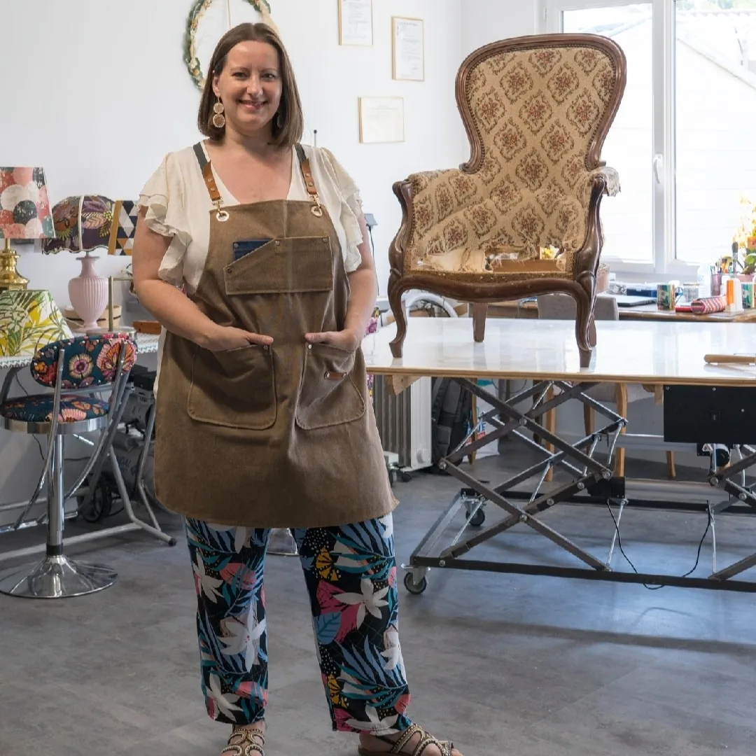 Séverine Templier, tapissier, debout dans son atelier de Saint-Mars-de-Coutais devant un fauteuil ancien à refaire